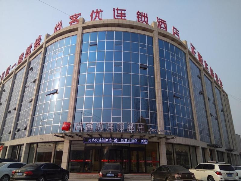um grande edifício com carros estacionados em frente em Thank Inn Plus Hotel Shandong Jining Liangshan County Xuji Zhengyang em Jining