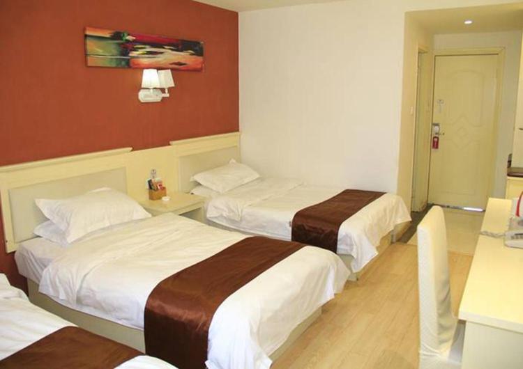 two beds in a hotel room with red walls at Thank Inn Plus Hotel Shandong Zaozhuang Central District Zhenxing road jipin street store in Zhaozhuang