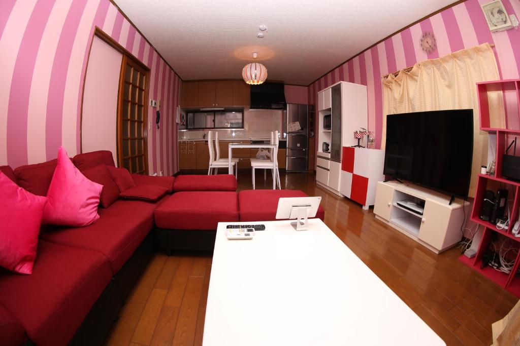 a living room with a red couch and a tv at Pop Culture House in Takayama