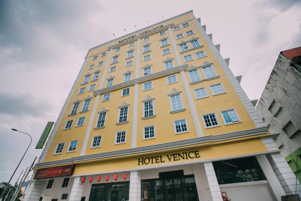 un grande edificio giallo con un furgoncino da hotel di Hotel Venice a Kuala Lumpur