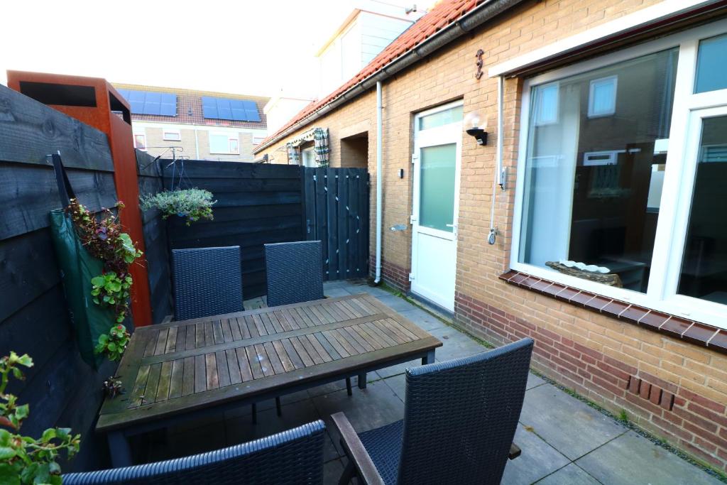 a small patio with a wooden table and chairs at Renovated Beach House in Egmond aan Zee