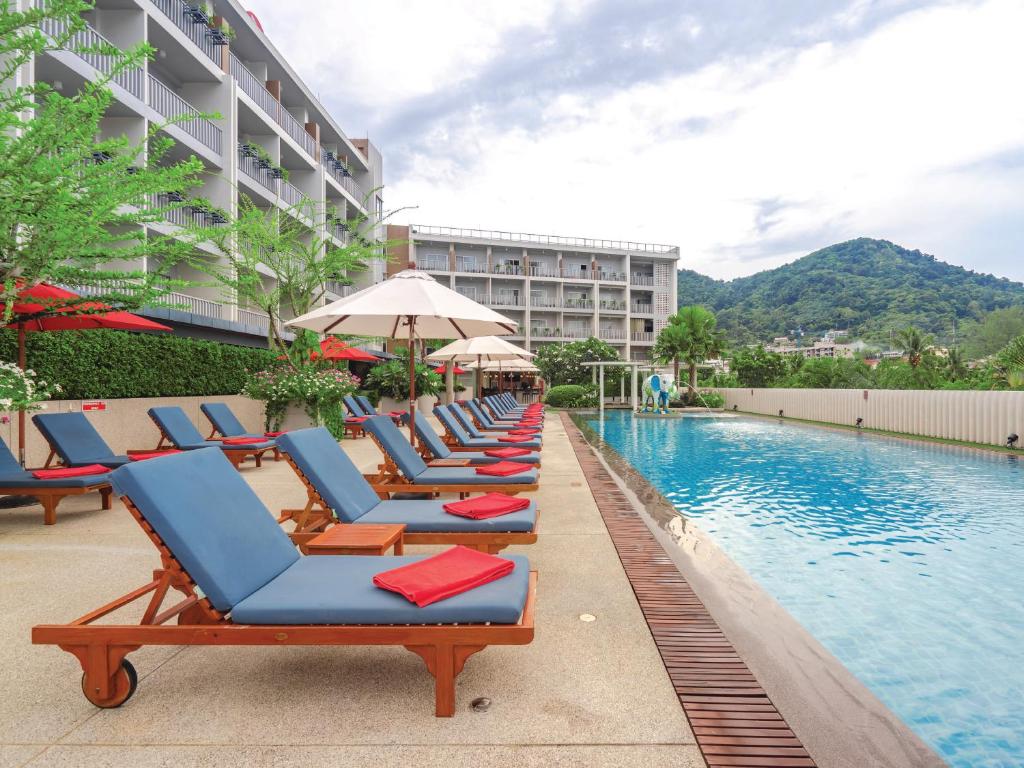 a row of lounge chairs next to a swimming pool at Ramada by Wyndham Phuket Deevana in Patong Beach