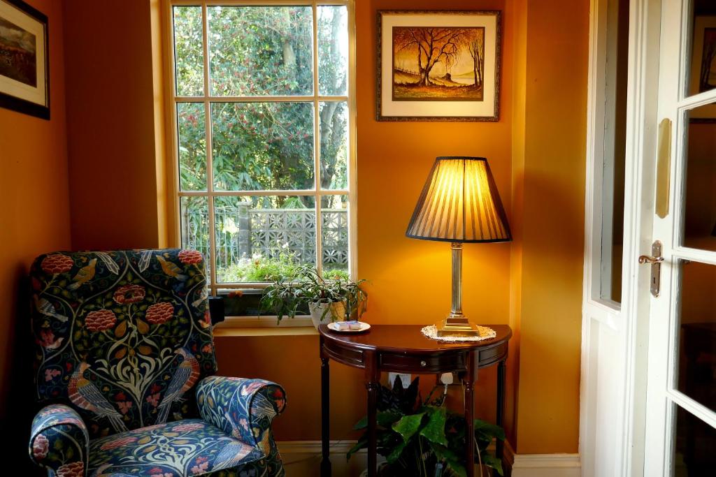 a room with a chair and a lamp on a table at Crookedstone House in Antrim