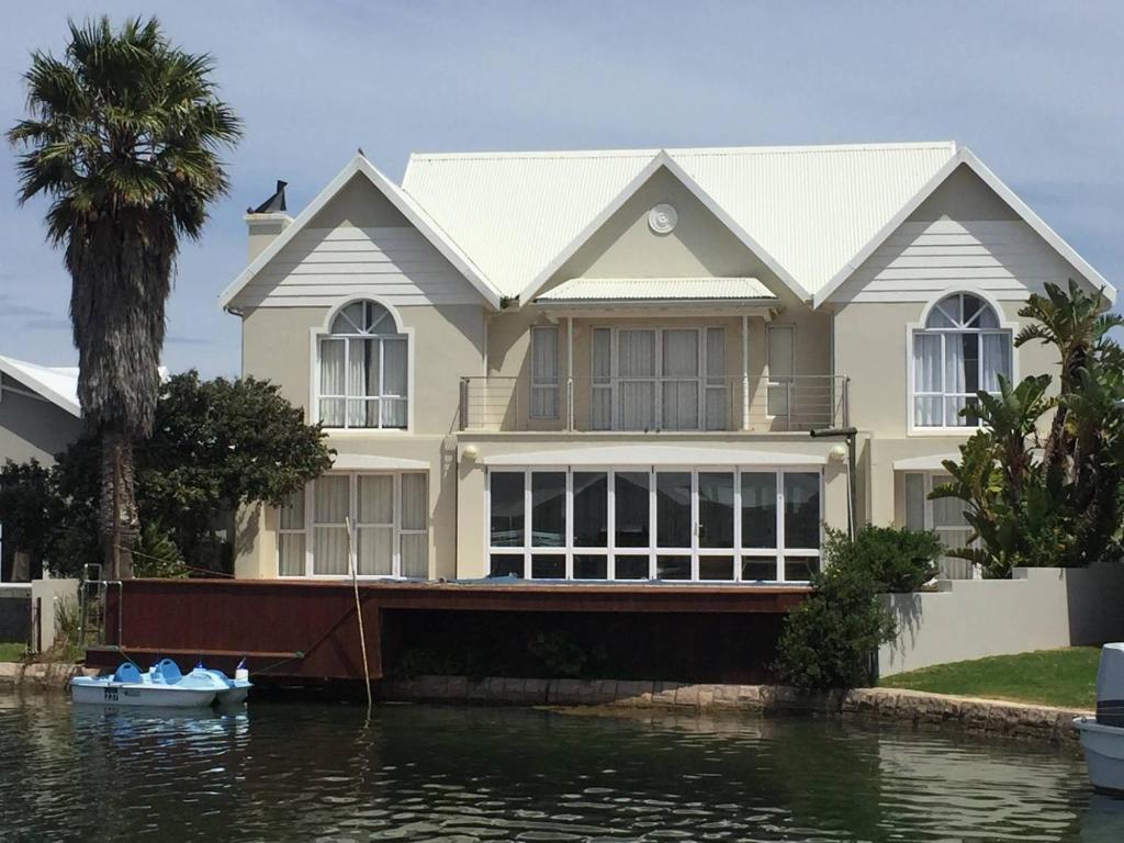 una casa en el agua con un barco delante en Waterside Living MM1404, en Jeffreys Bay