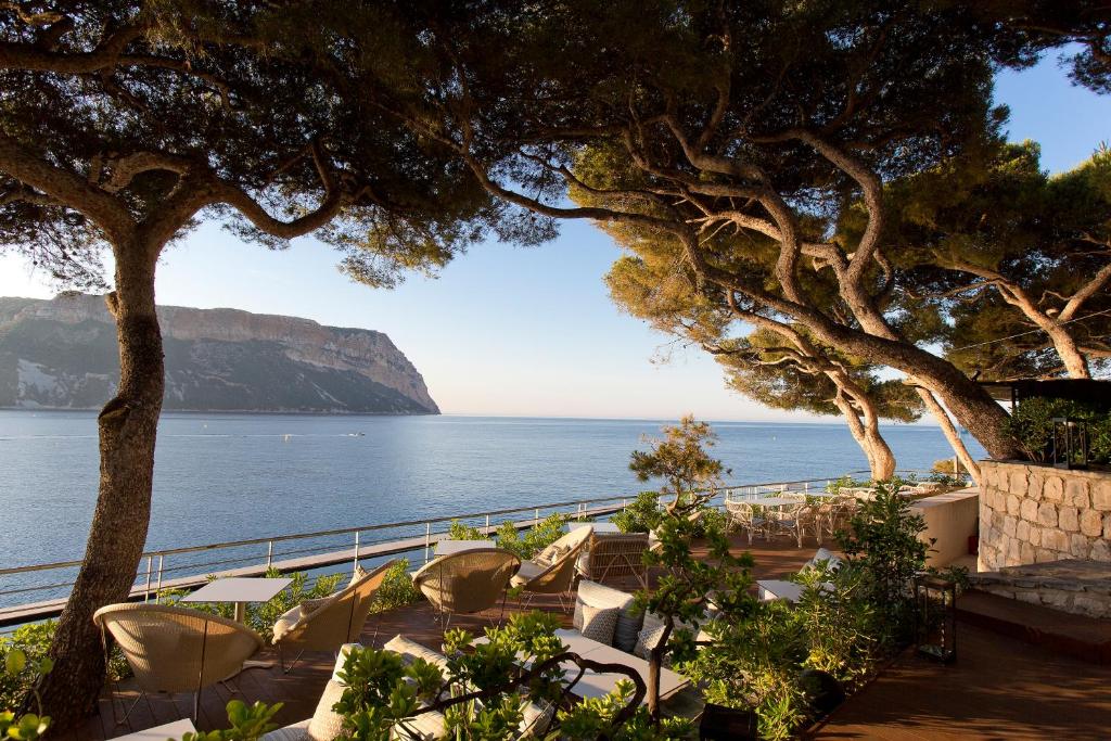 a view of the ocean from a resort with chairs and trees at Hôtel Les Roches Blanches Cassis in Cassis