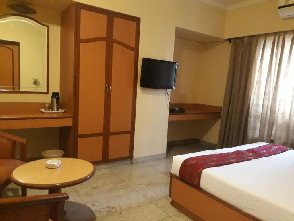 a hotel room with a bed and a small table at The Samrat Hotel near Pune Railway Station in Pune