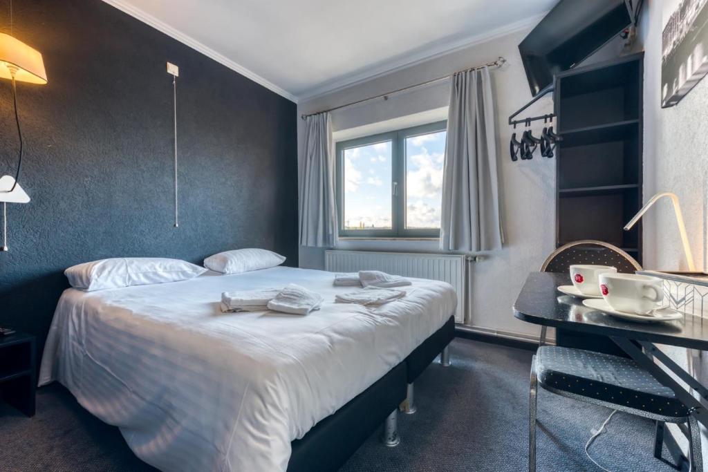 a hotel room with a bed and a desk at Hôtel de la Gare in Visé