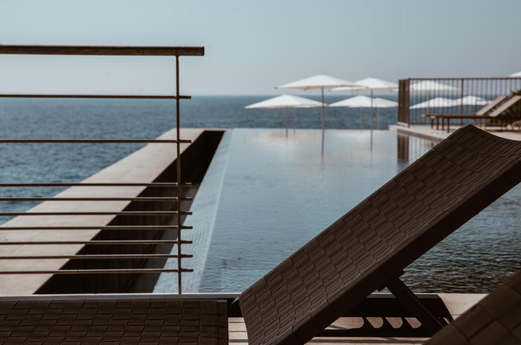 a swimming pool with a bench next to the water at Hôtel Les Roches Blanches Cassis in Cassis