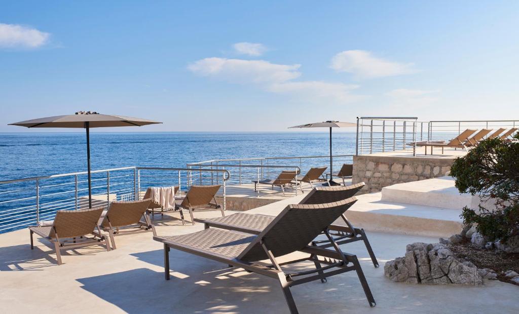 a group of chairs and umbrellas on a deck at Hôtel Les Roches Blanches Cassis in Cassis