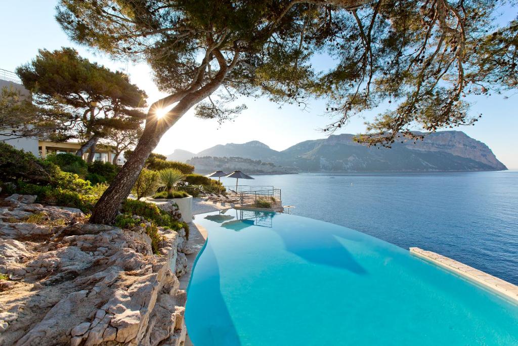 a swimming pool with a view of the water at Hôtel Les Roches Blanches Cassis in Cassis