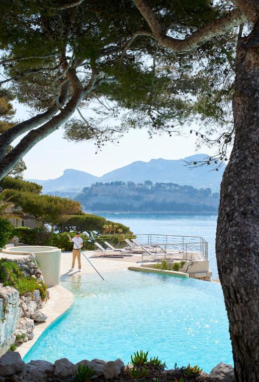 a person standing in a swimming pool next to the water at Hôtel Les Roches Blanches Cassis in Cassis