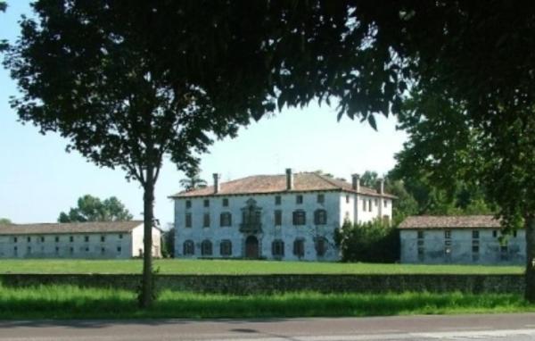 a large white building in the middle of a field at Villa Mainardi Agriturismo in Camino al Tagliamento