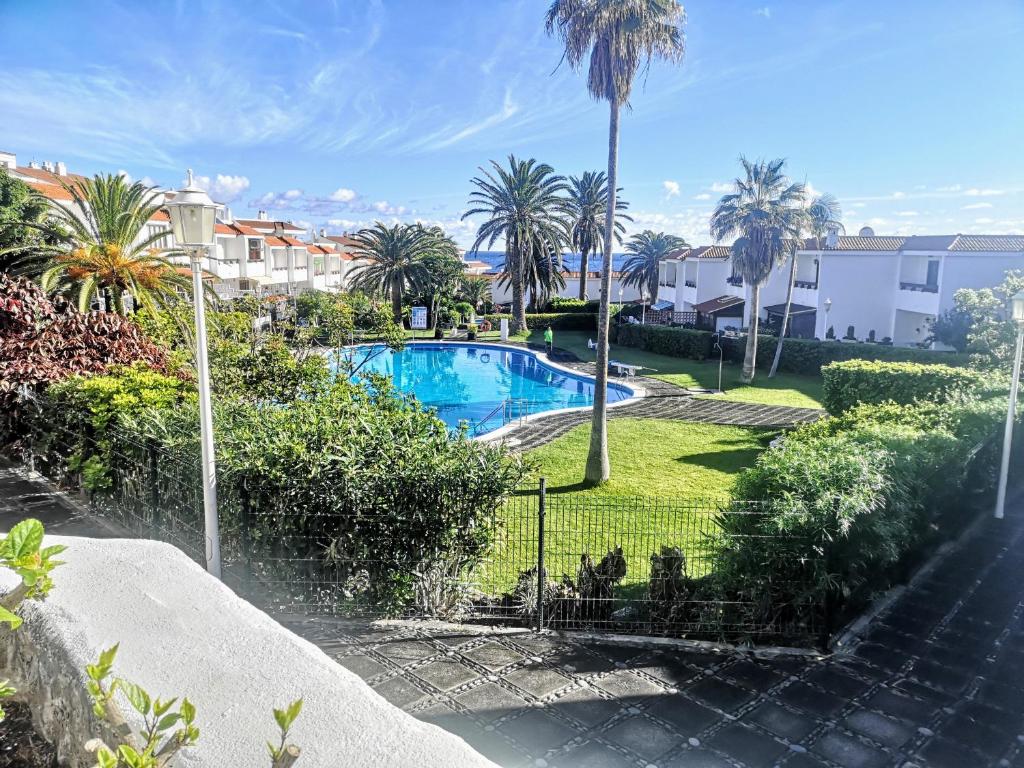 una piscina en un patio con palmeras en VV Dúplex Los Cancajos "by henrypole home", en Los Cancajos