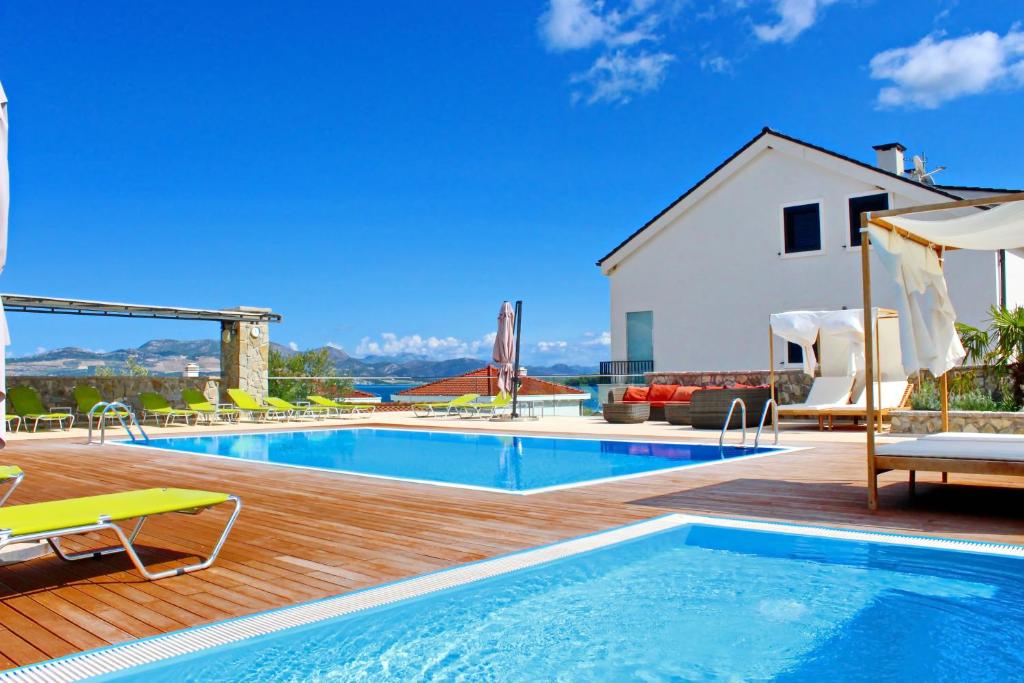 una piscina en una terraza de madera junto a una casa en Apartments Kula, en Janjina