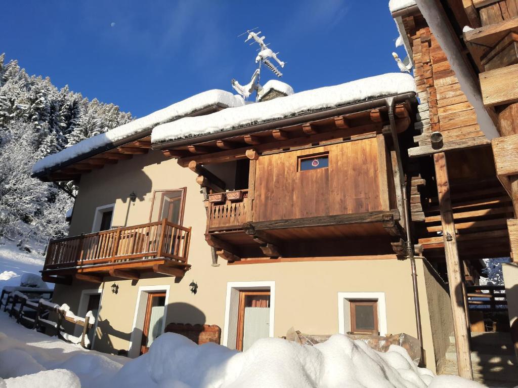 a log cabin with a balcony in the snow at L'Abreny in Brusson