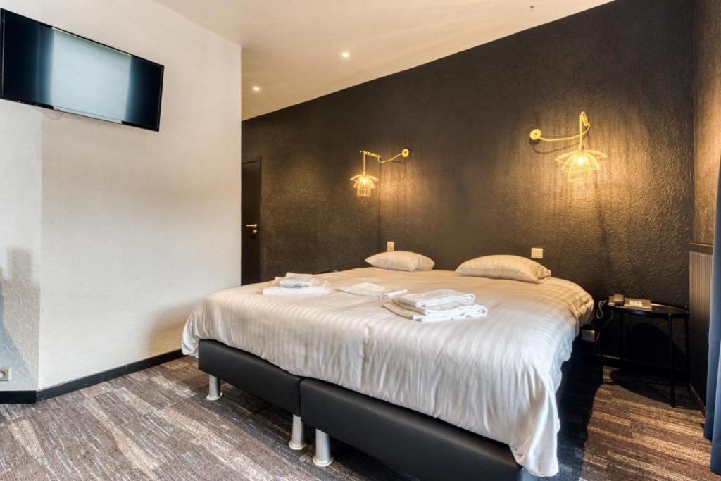 a bedroom with a large bed and a flat screen tv at Hôtel Mosa in Hermalle-sous-Argenteau