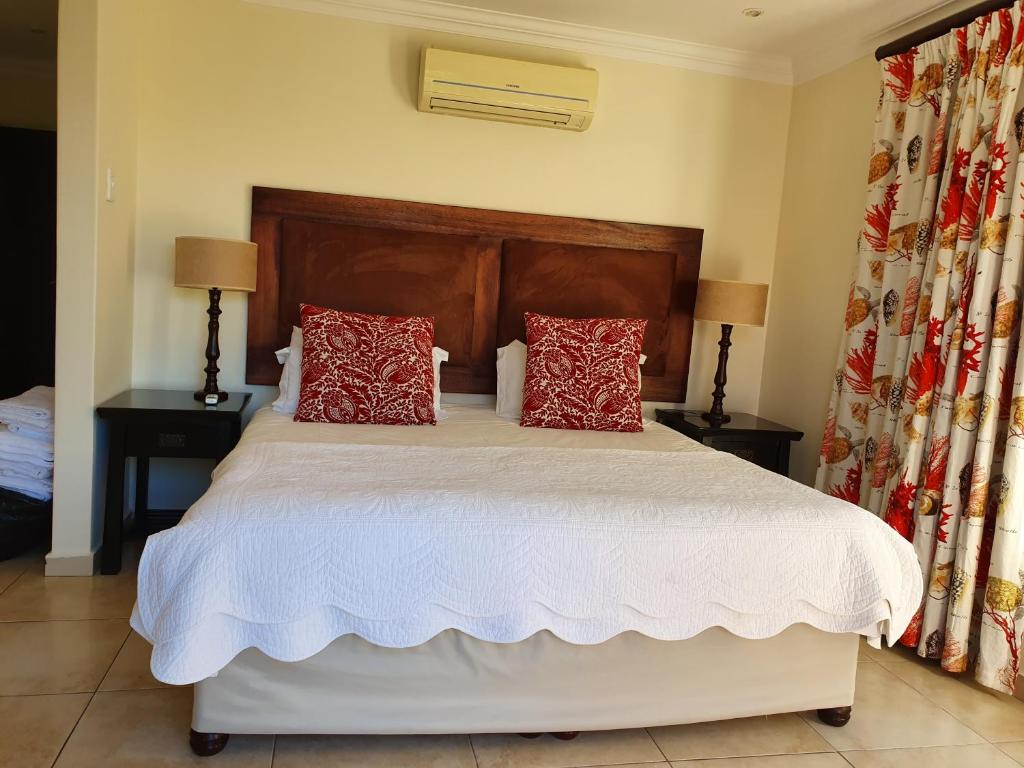 a bedroom with a large bed with red pillows at Zimbali Villa 54 in Ballito