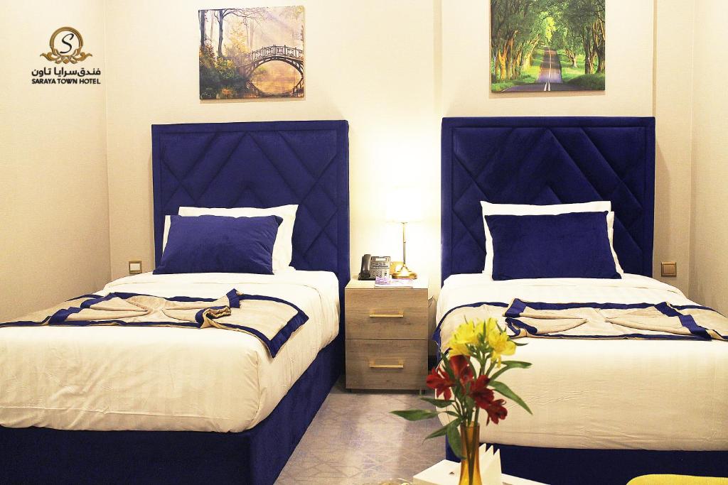 two beds with blue headboards in a bedroom at Saraya Palace Hotel in Doha