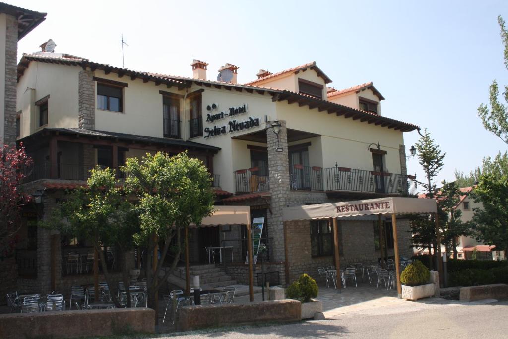 Apart-Hotel Selva Nevada في La Virgen de la Vega: مبنى امامه طاولات وكراسي