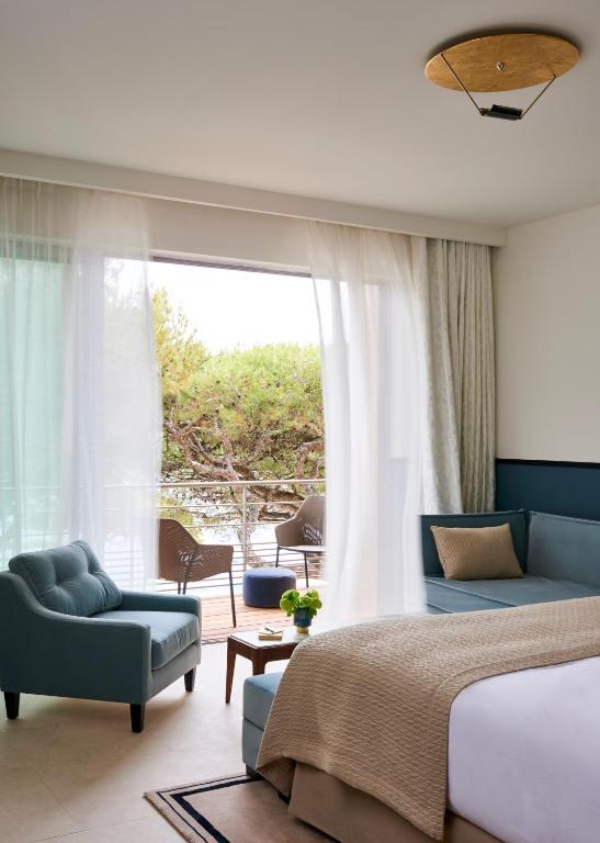 a bedroom with a bed and a couch and a window at Hôtel Les Roches Blanches Cassis in Cassis