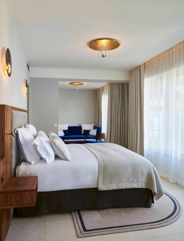 a bedroom with a large bed and a large window at Hôtel Les Roches Blanches Cassis in Cassis