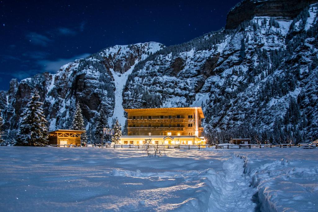 een gebouw in de sneeuw voor een berg bij Pederü in San Vigilio Di Marebbe