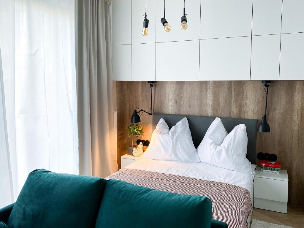 łóżko z białymi poduszkami i kanapą w pokoju w obiekcie ONE Apartamenty Gąsiorowskich 4 w Poznaniu