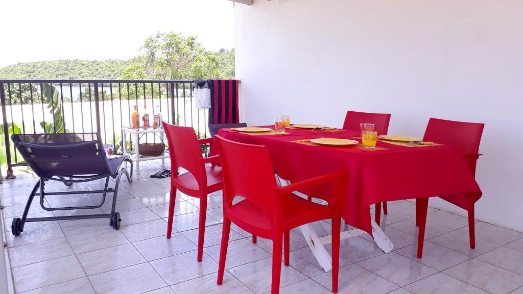 d'une table à manger rouge et de chaises sur un balcon. dans l'établissement Appartement de 2 chambres avec vue sur la mer jardin clos et wifi a Le Vauclin, au Vauclin