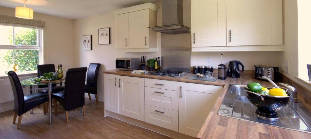 a kitchen with white cabinets and a table with a bowl of fruit at Osprey in Bracknell