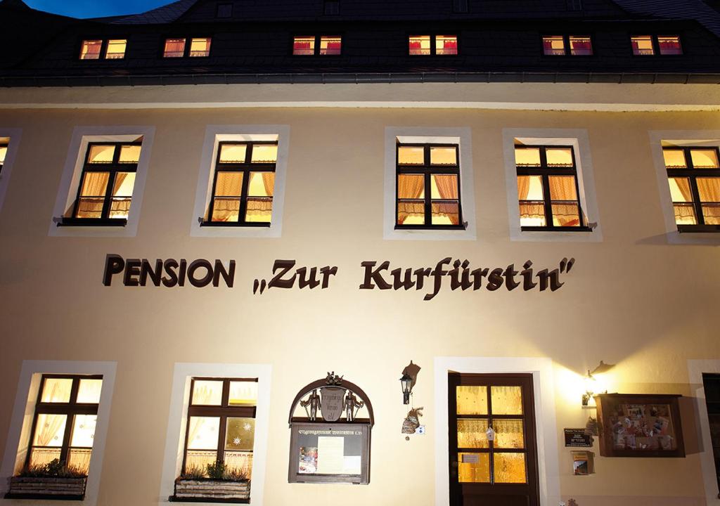 a white building with a sign on the side of it at Pension zur Kurfürstin in Wolkenstein