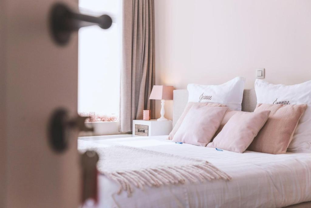 una camera da letto con letto, lenzuola e cuscini bianchi di Jeanne a Nieuwpoort