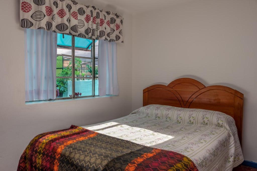 een slaapkamer met een bed en een raam bij Posada Azul Cusco in Cuzco