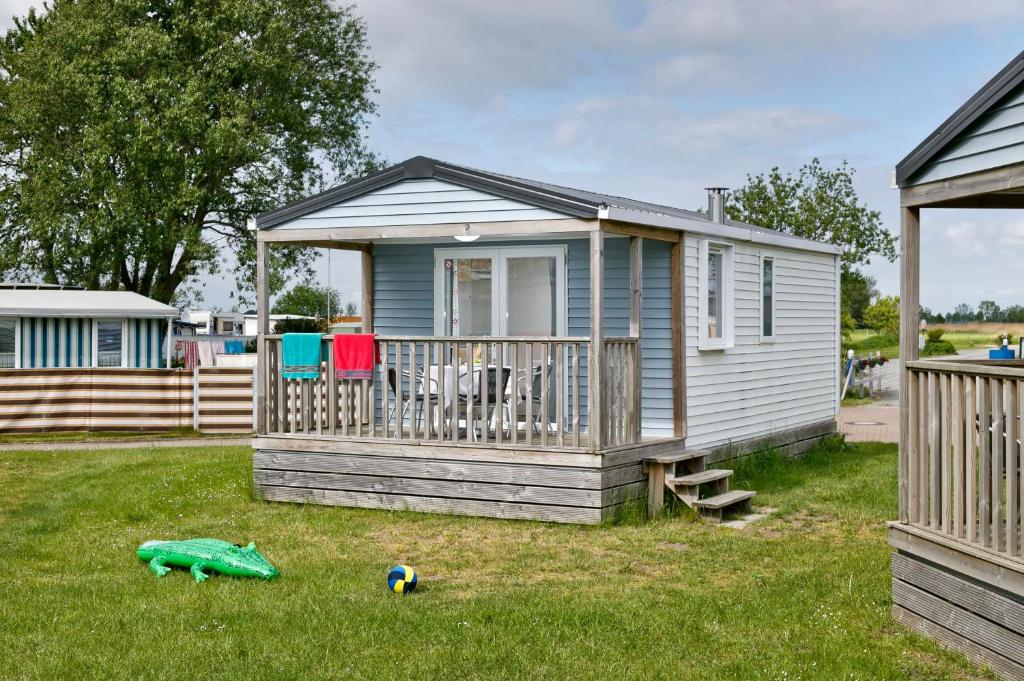 a small house with a deck and a yard at KNAUS Campingpark Eckwarderhörne in Eckwarderhörne