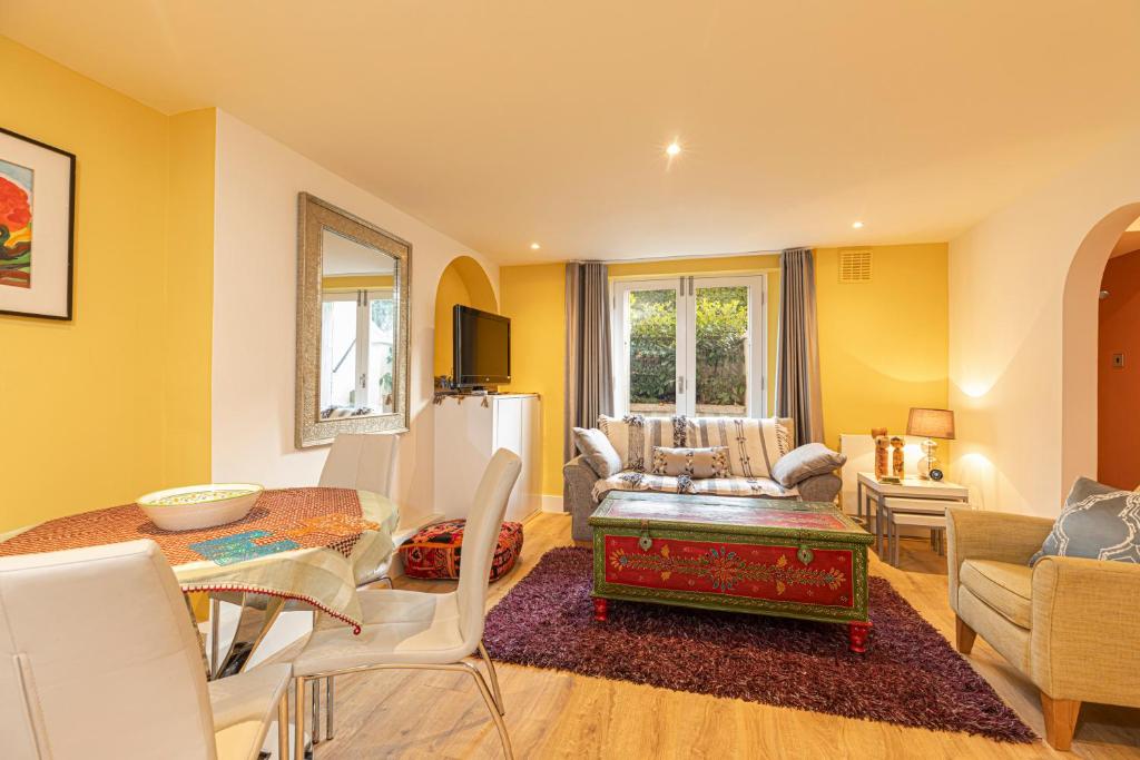una sala de estar con paredes amarillas y una mesa. en Charming 2 bed with garden in Notting Hill, en Londres