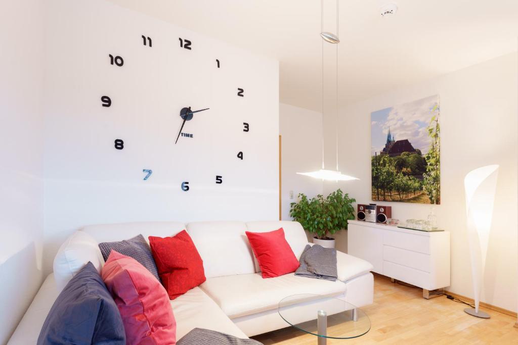 a living room with a white couch and a clock on the wall at Wohnung mit Blick auf die Zitadelle Petersberg - 3 Zimmer in Erfurt