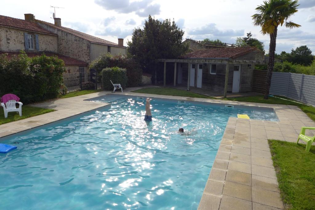a person swimming in a swimming pool in a backyard at La Frapperie in Beaurepaire