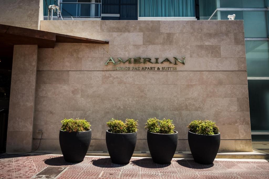 un grupo de plantas en macetas frente a un edificio en Amérian Carlos Paz & Suites en Villa Carlos Paz