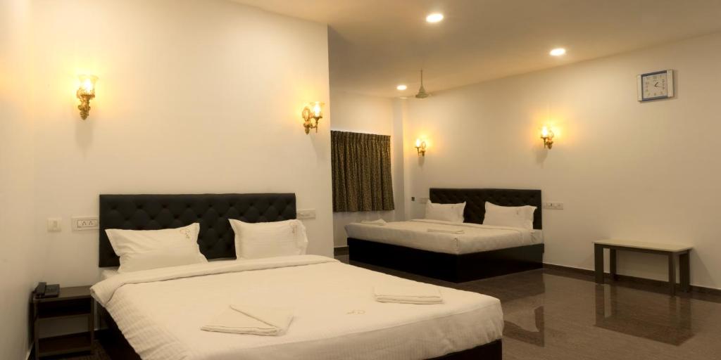 a hotel room with two beds and two tables at COSY CHAMBRE in Puducherry