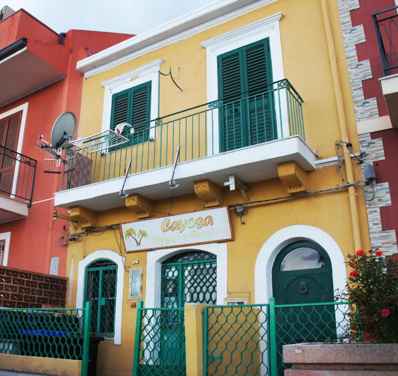 een geel gebouw met groene deuren en een balkon bij Casa Vacanze Cayohouse in Messina