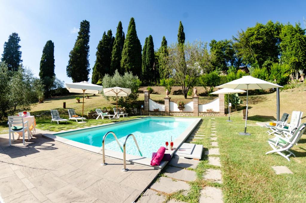 a swimming pool in a yard with chairs and umbrellas at Villa al Borghetto in Uzzano