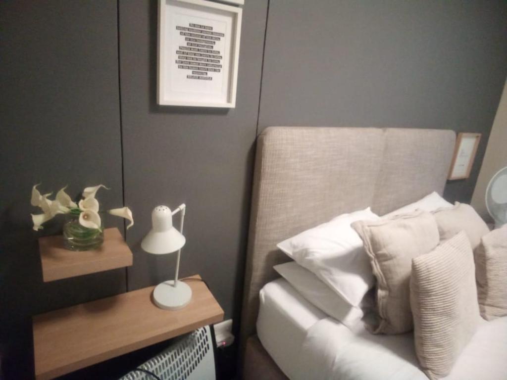 1 dormitorio con 1 cama y 1 mesa con lámpara en Cosmopolitan Accommodation Group, en Johannesburgo