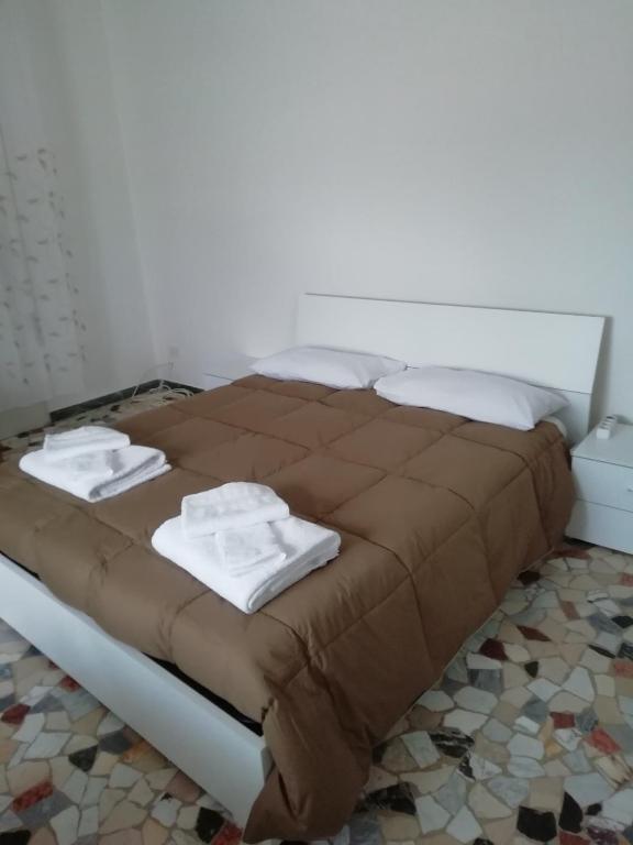 a bed with brown sheets and white towels on it at Affittacamere Mark in Faenza