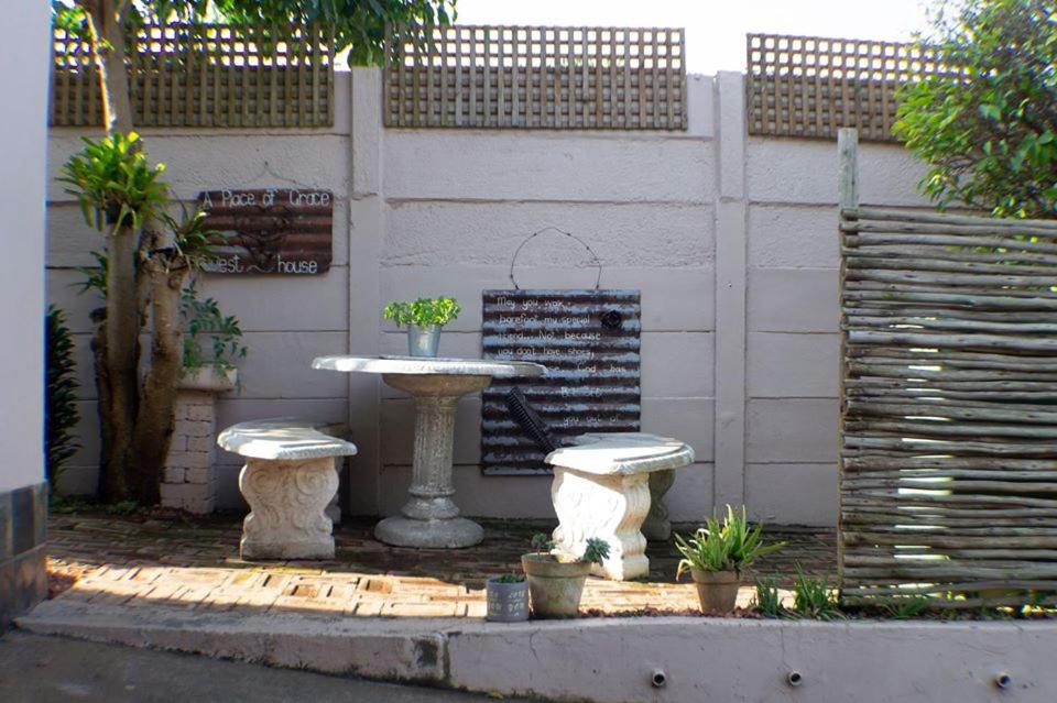 a stone fountain with two seats in front of a wall at A Place of Grace in Durban
