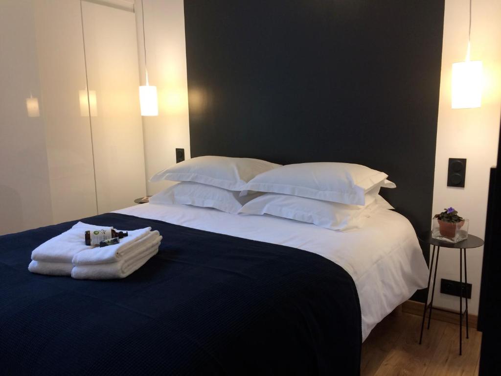 een slaapkamer met een groot bed met witte lakens en kussens bij LE NID DES ROIS, à 2 pas de la Cathédrale in Reims