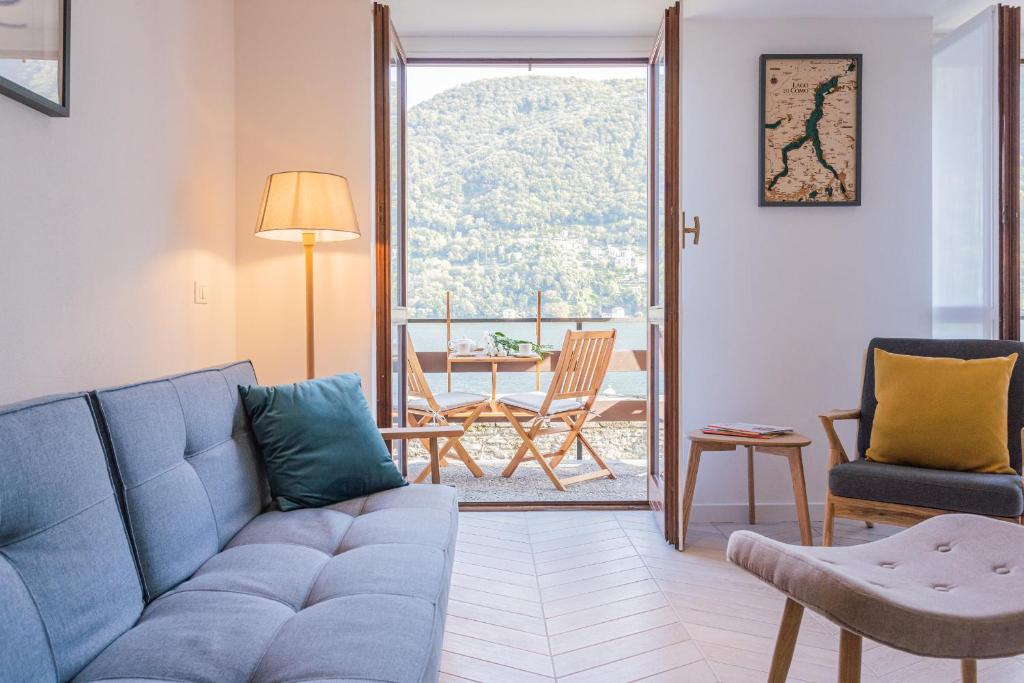 uma sala de estar com um sofá azul e uma varanda em Your Private Harbour on Lake Como by Rent All Como em Laglio