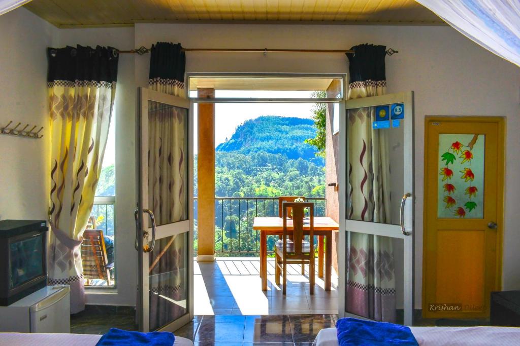 
a room with a bed, table, chairs and a window at Will Guest Homestay in Ella
