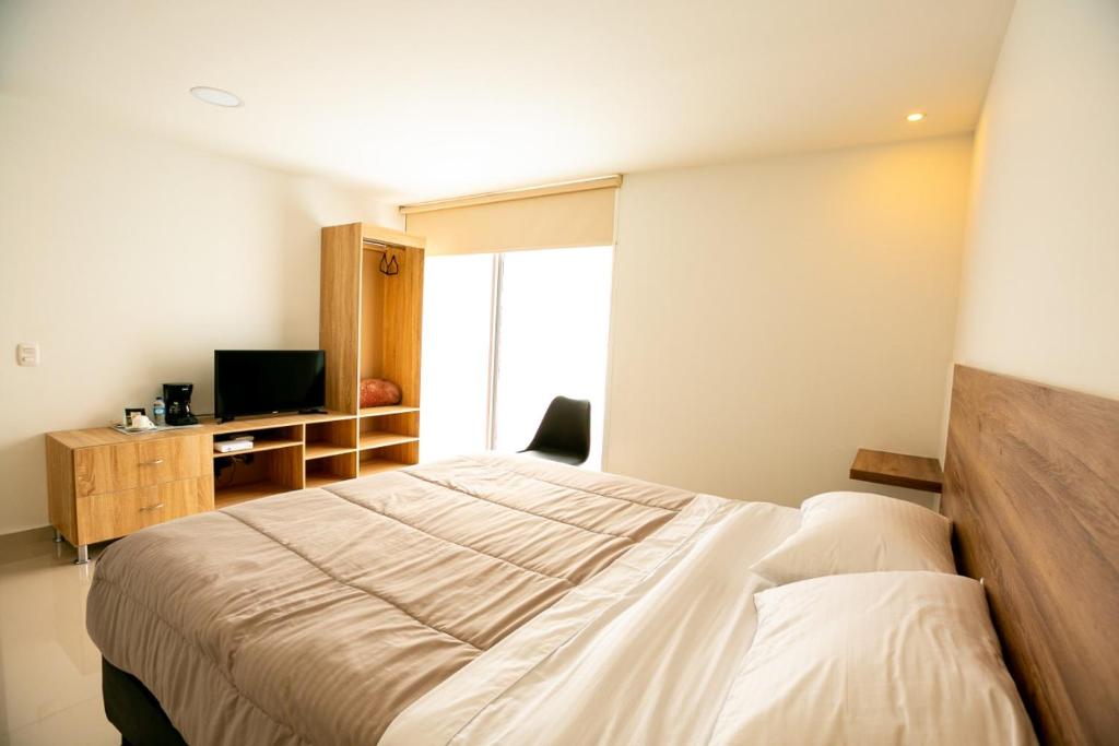 1 dormitorio con 1 cama grande y TV en Orange Wild, en Bogotá