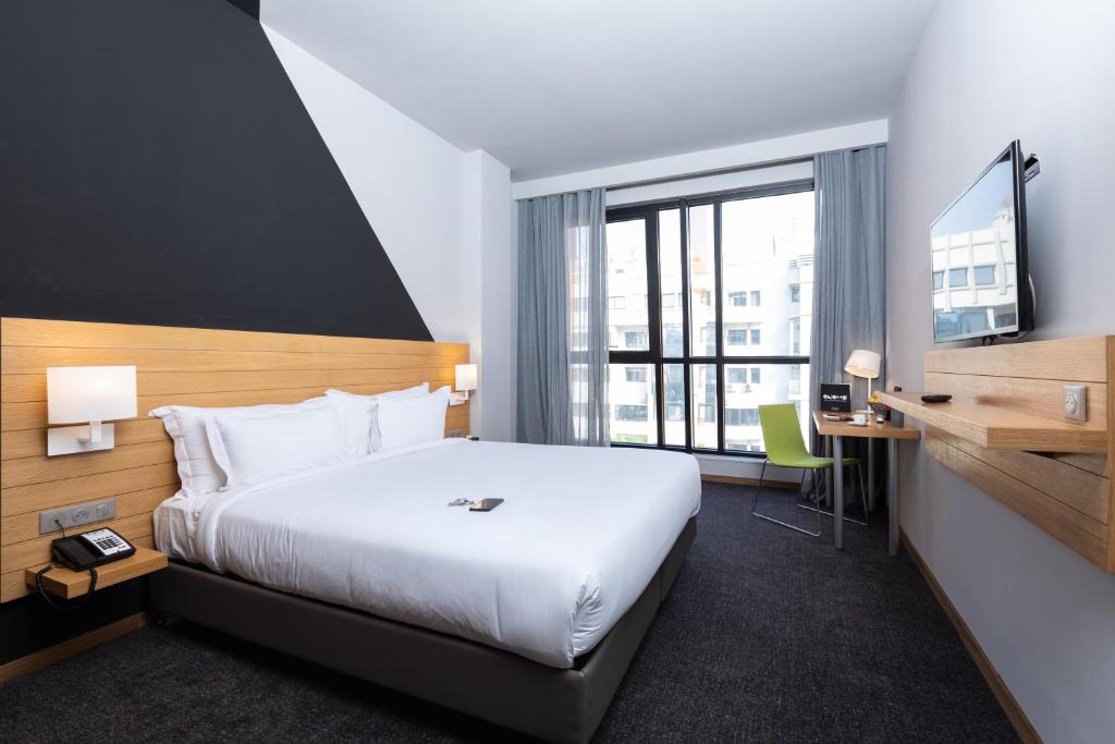 una camera d'albergo con un grande letto e una scrivania di ONOMO Hotel Casablanca City Center a Casablanca