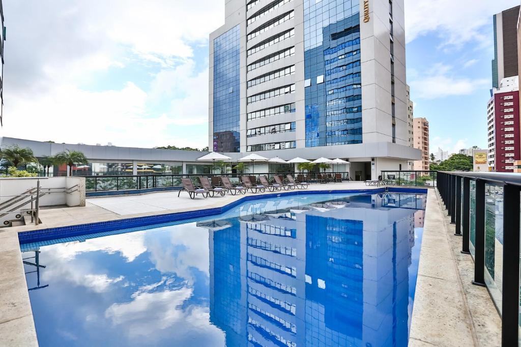 uma piscina com cadeiras e um edifício em Quality Hotel & Suítes São Salvador em Salvador