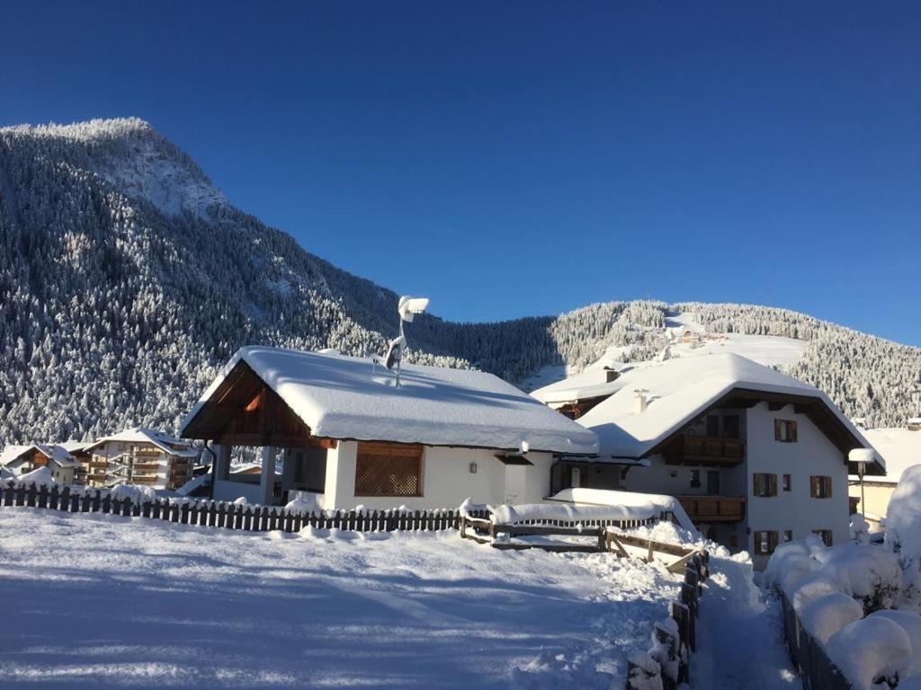 a building covered in snow with mountains in the background at App. Daverda Walter Strada al Plan Dessora 26 in San Vigilio Di Marebbe